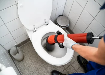 Plombier débouchant un WC avec une pompe manuelle